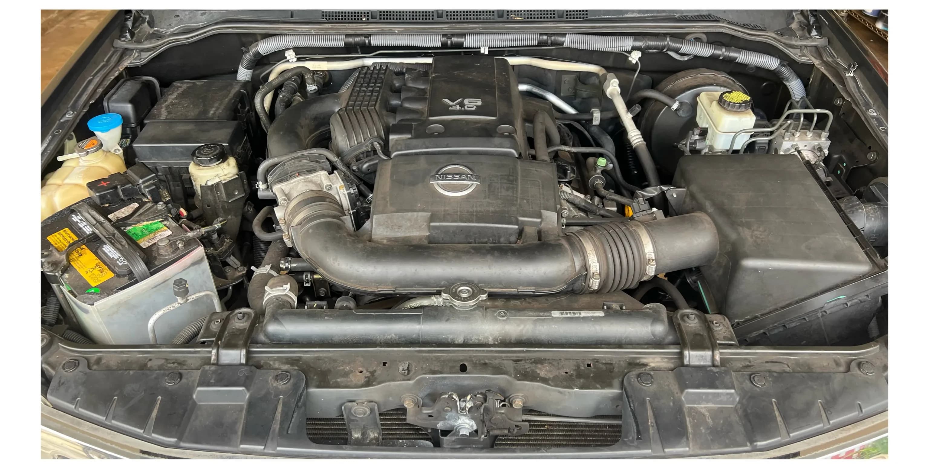 Dusty Nissan Frontier engine bay before specialty cleaning