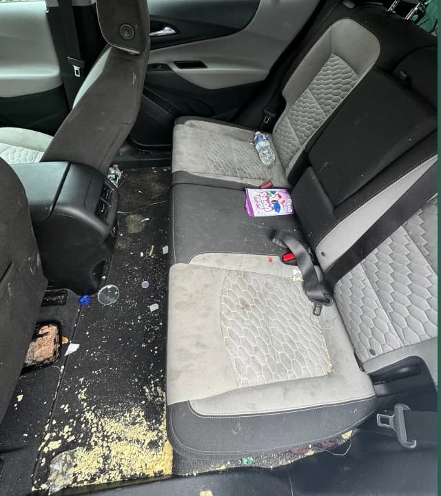 Vehicle rear seat and floor with debris before interior detailing